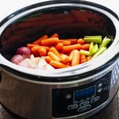 Process shot showing how to cook pork chops with vegetables in a slow cooker.