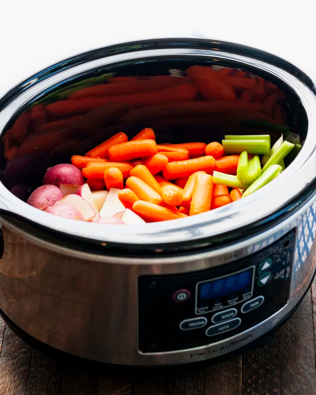 Process shot showing how to cook pork chops with vegetables in a slow cooker.