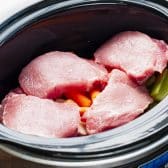 Boneless pork chops in a Crock Pot with vegetables.