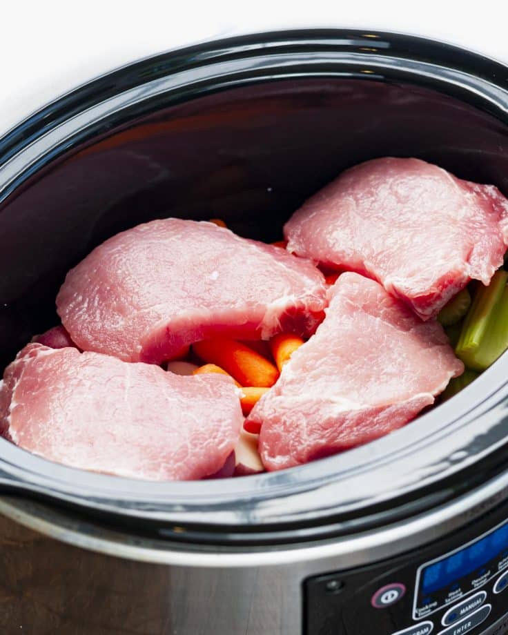 Boneless pork chops in a Crock Pot with vegetables.