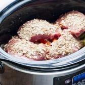 Sprinkling onion soup mix on top of pork chops in a Crock Pot.