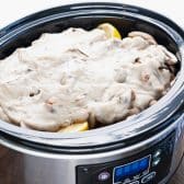 Cream of mushroom soup on top of mushrooms and pork chops in a slow cooker.