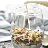 Pouring milk into a glass of the best homemade muesli recipe.