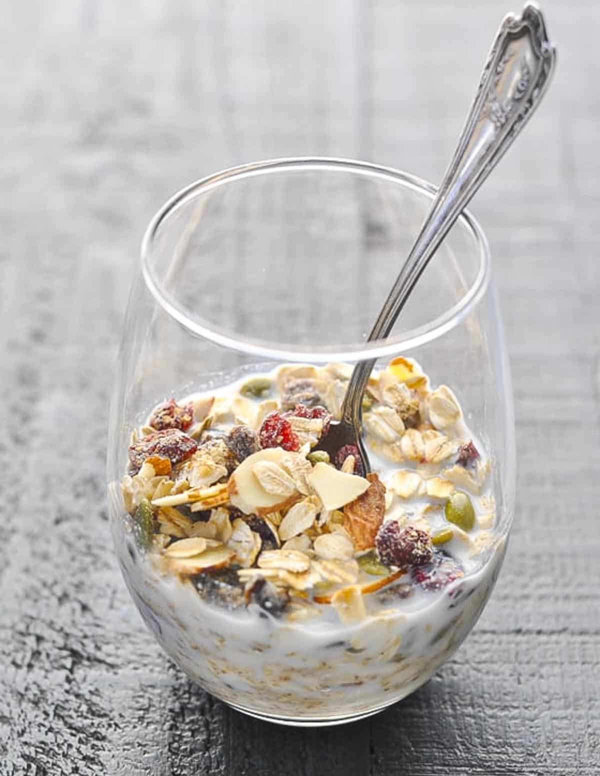 Swiss muesli in a glass with milk and a spoon.