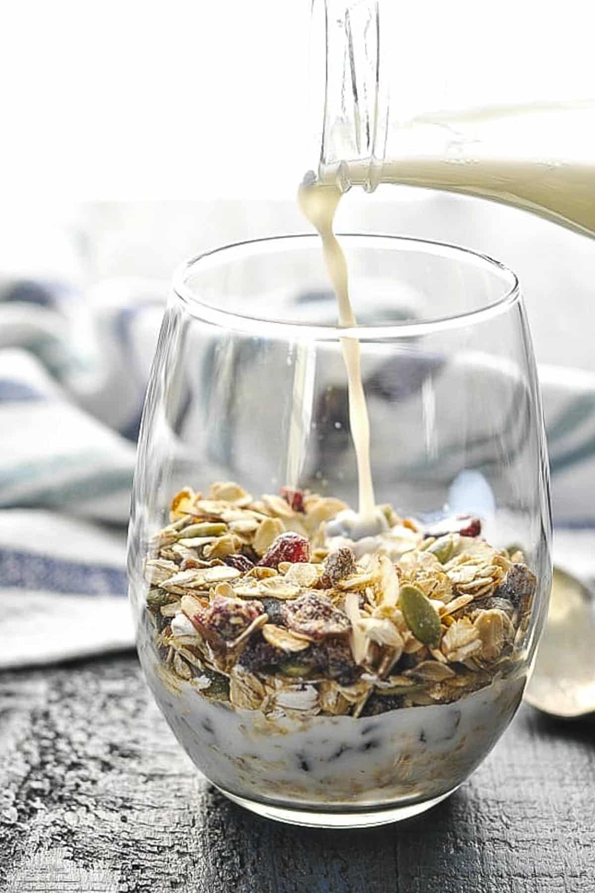 Pouring milk into a glass of the best homemade muesli recipe.