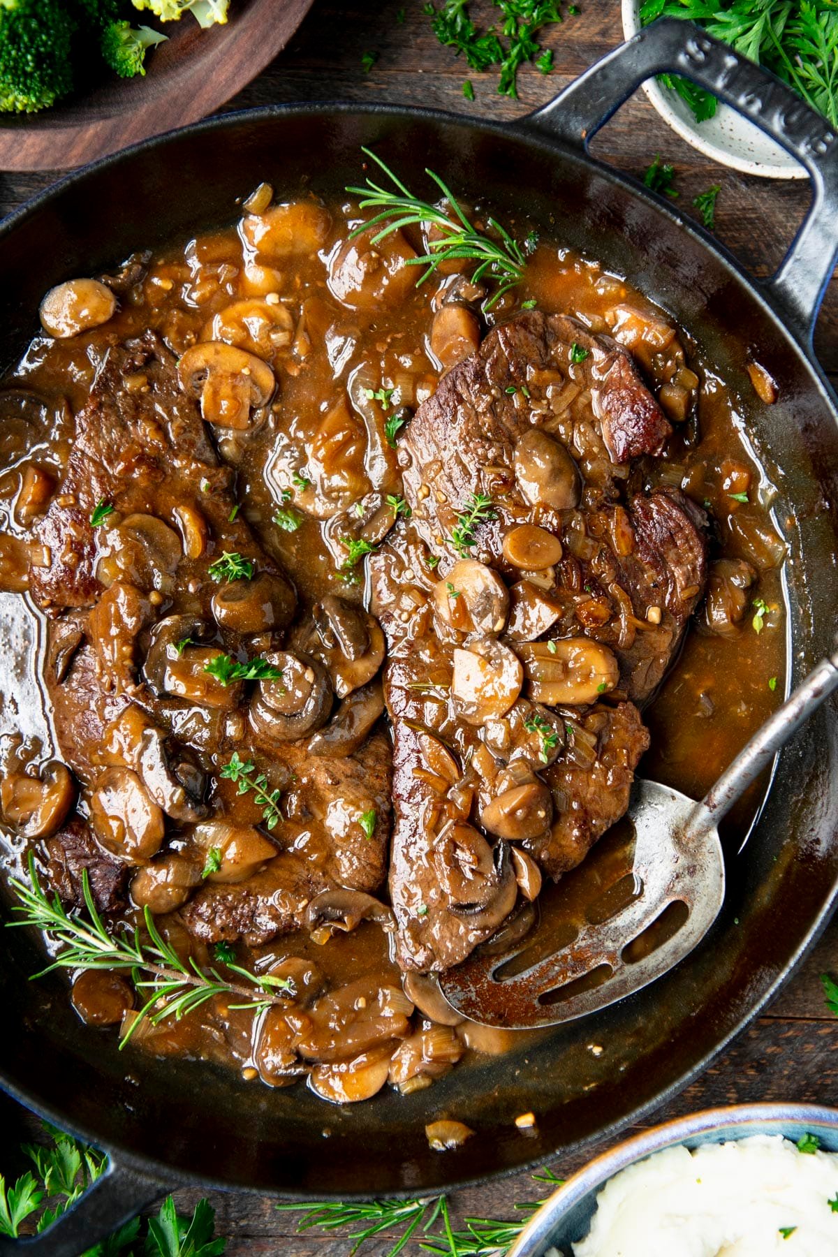 Overhead shot of round steak with mushroom and onion gravy in a cast iron skillet.