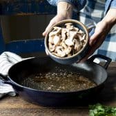 Adding mushrooms to a pan.