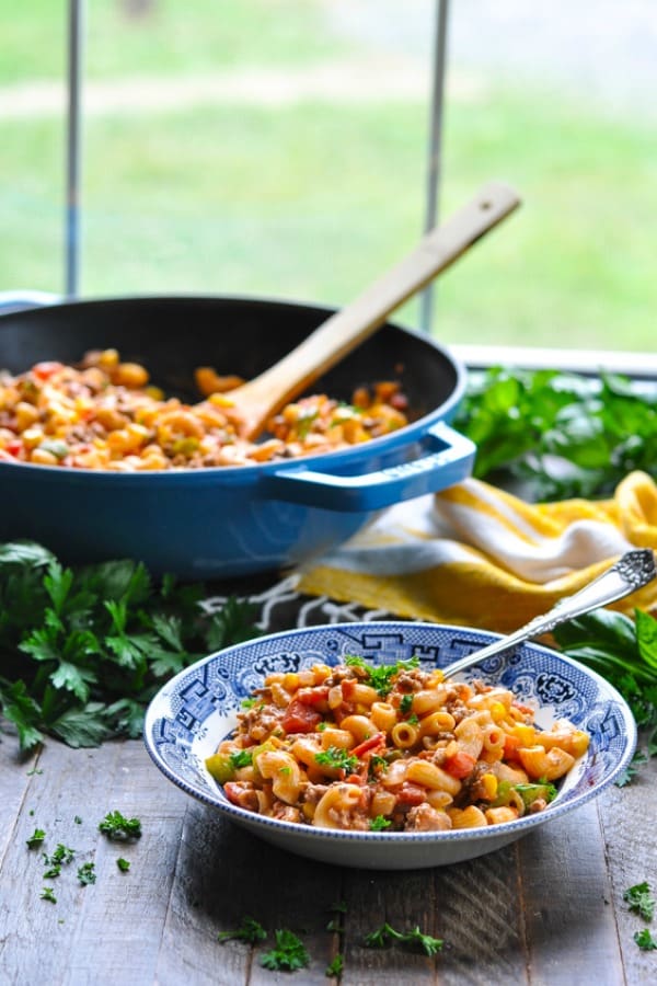 Front shot of ground beef pasta on a table in a serving bowl with big skillet in background