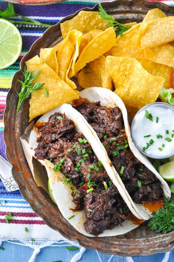 Overhead shot of crock pot beef barbacoa on a plate with a side of chips