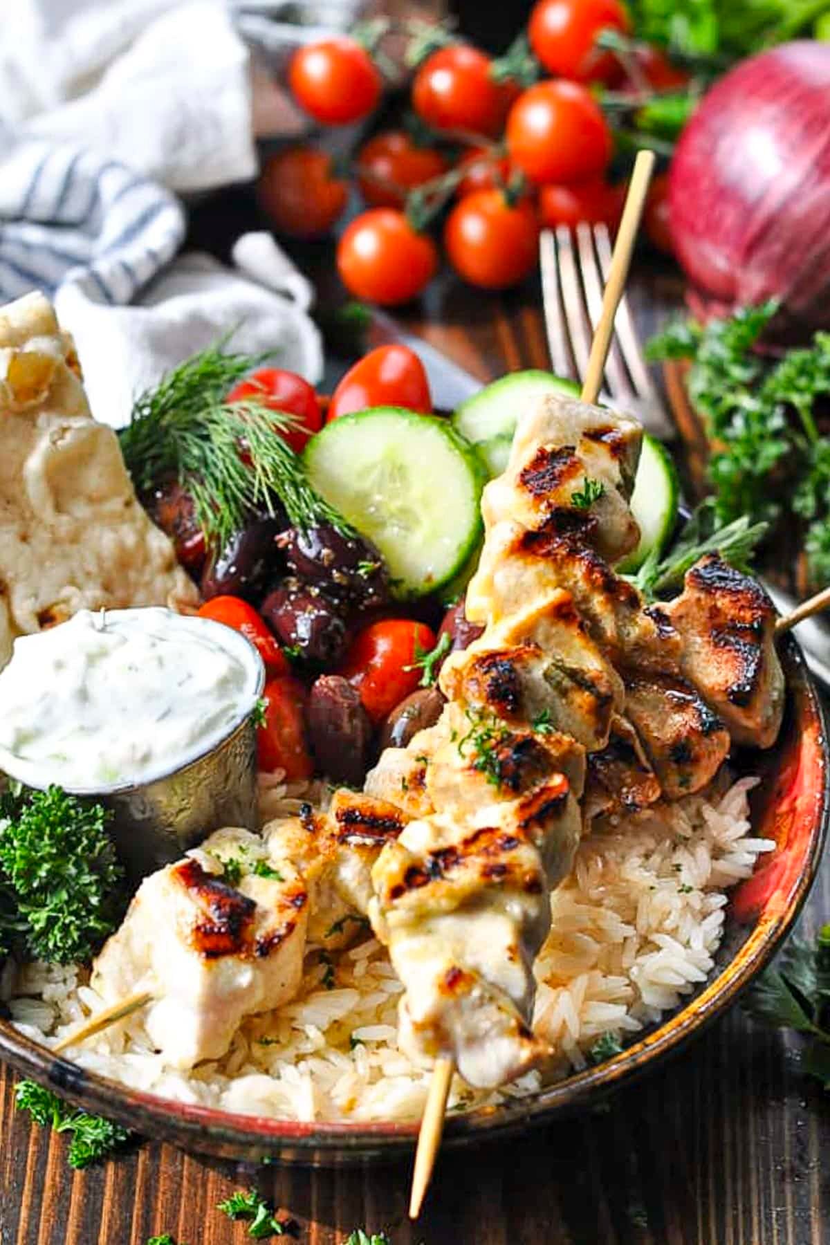 Front shot of chicken souvlaki in a bowl with tzatziki and pita.