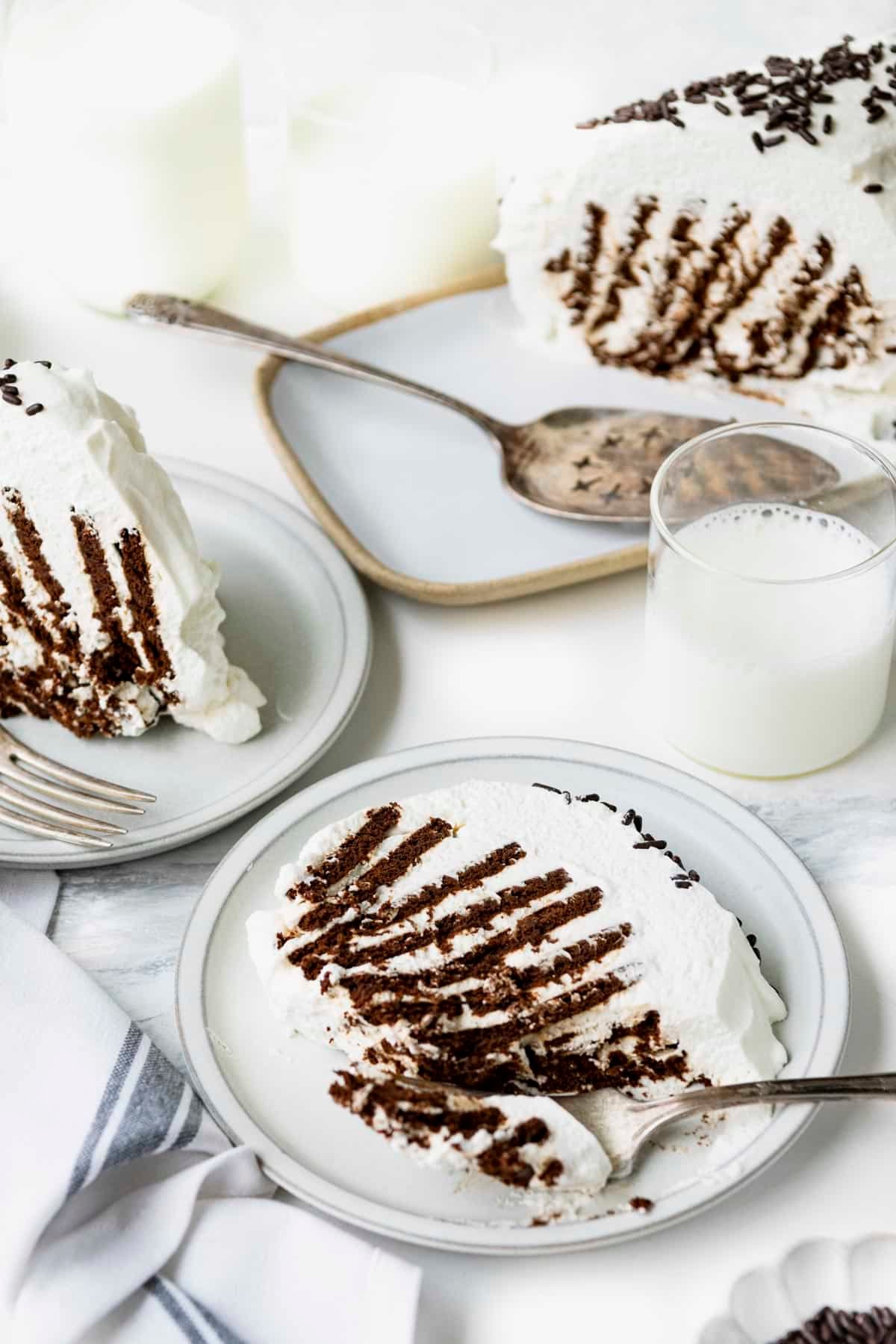 Slice of icebox cake on a white plate on a marble table.
