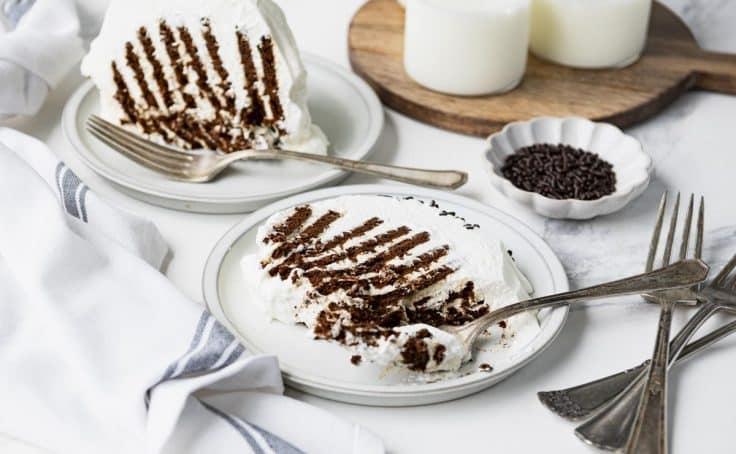 Horizontal shot of a slice of chocolate icebox cake on a white plate.