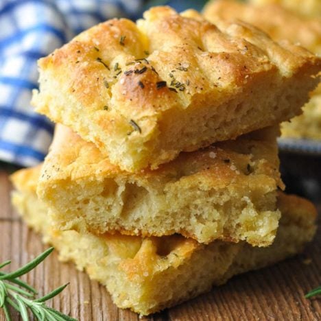 Square close up of stacked foccacia bread on a wooden board.