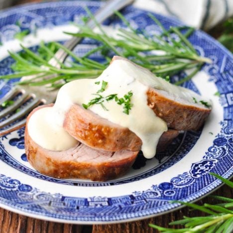 Square side shot of a plate of sliced roasted pork tenderloin with mustard sauce.