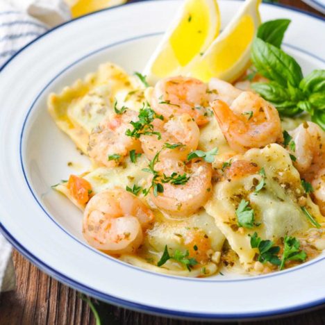 Square close up shot of shrimp with ravioli on a blue and white plate.