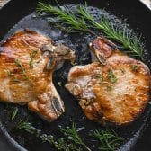 Horizontal overhead image of the best pork chop brine recipe on pork chops in a cast iron skillet.