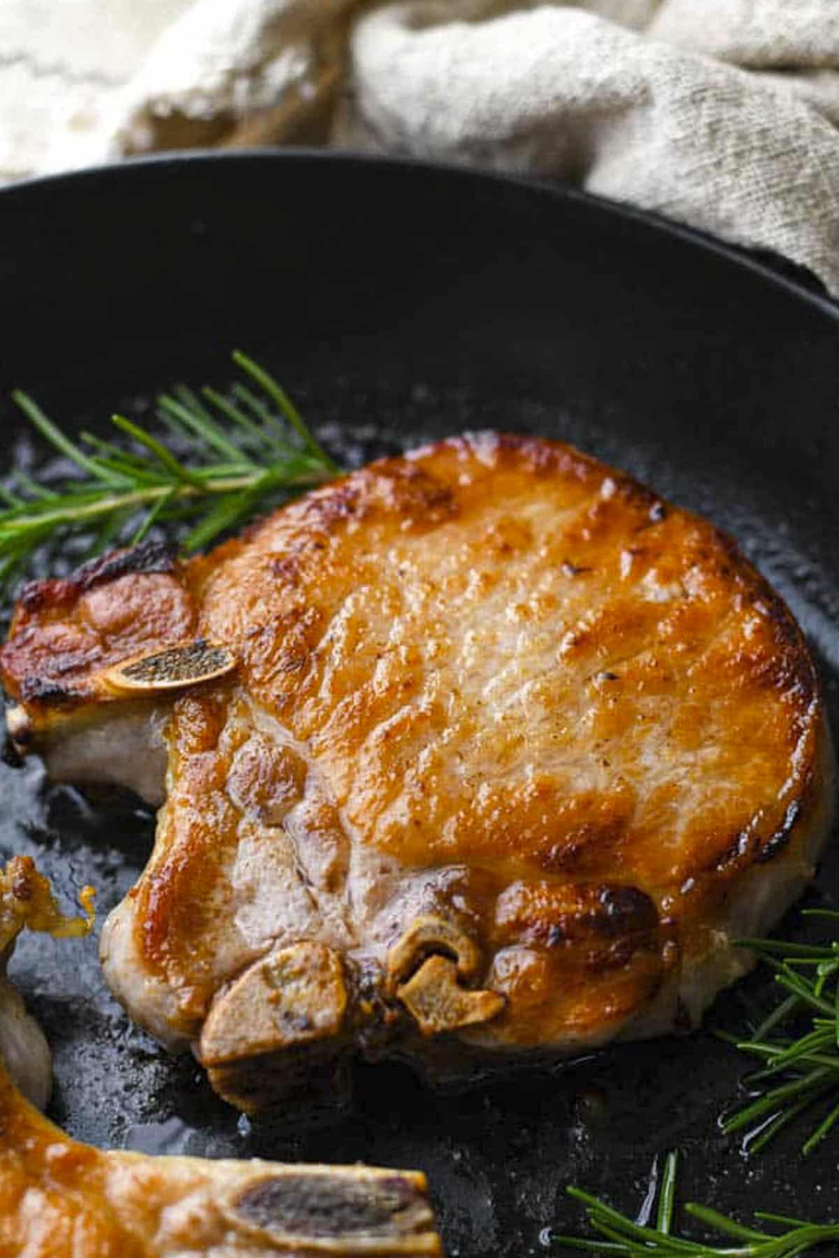 Side shot of a bone-in pork chop flavored with the best garlic rosemary pork chop brine.