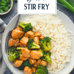 Overhead shot of a bowl of chinese chicken and broccoli stir fry with a side of rice and text title overlay