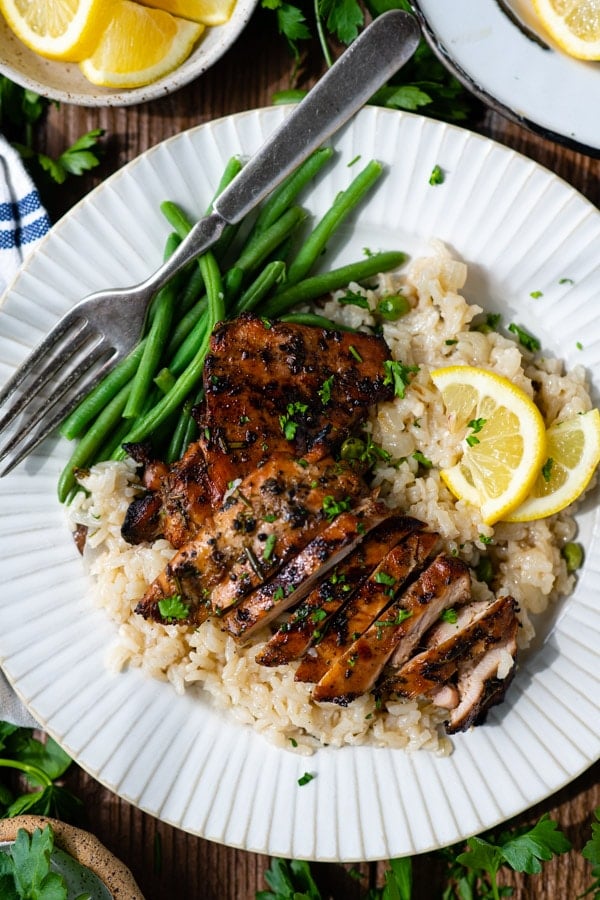 Overhead shot of marinated chicken thighs with rice and green beans.