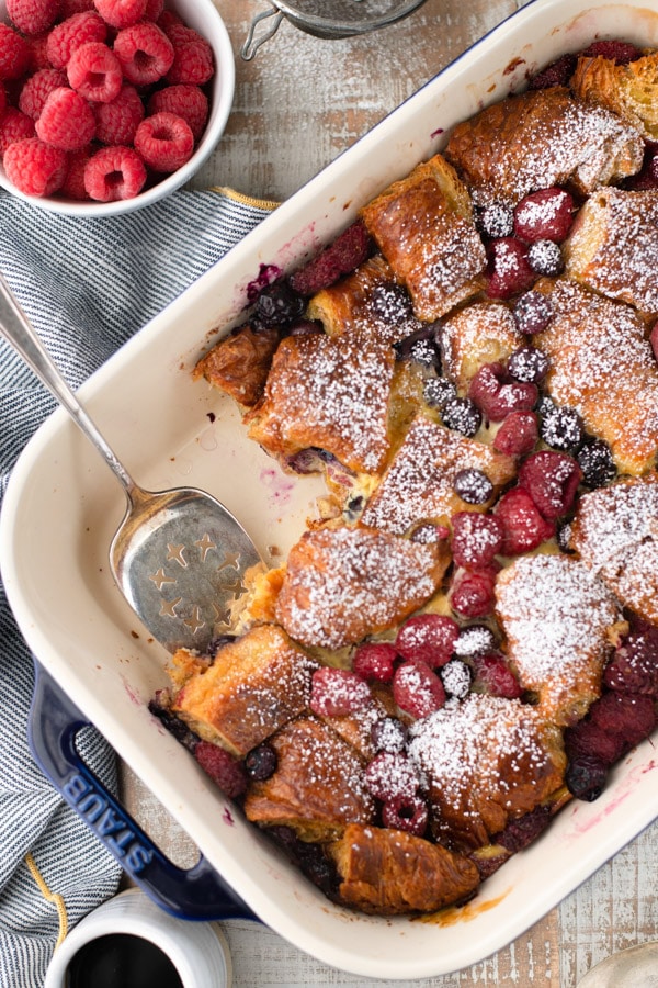Overhead shot of a make ahead croissant breakfast casserole in a baking dish with fresh berries