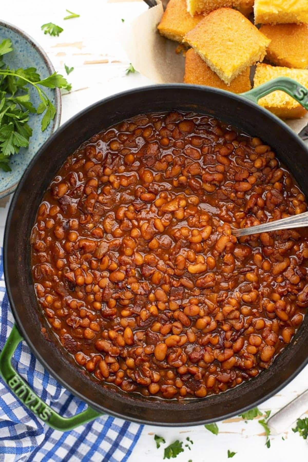 Close overhead image of the best homemade baked beans recipe in a Dutch oven on a white table.