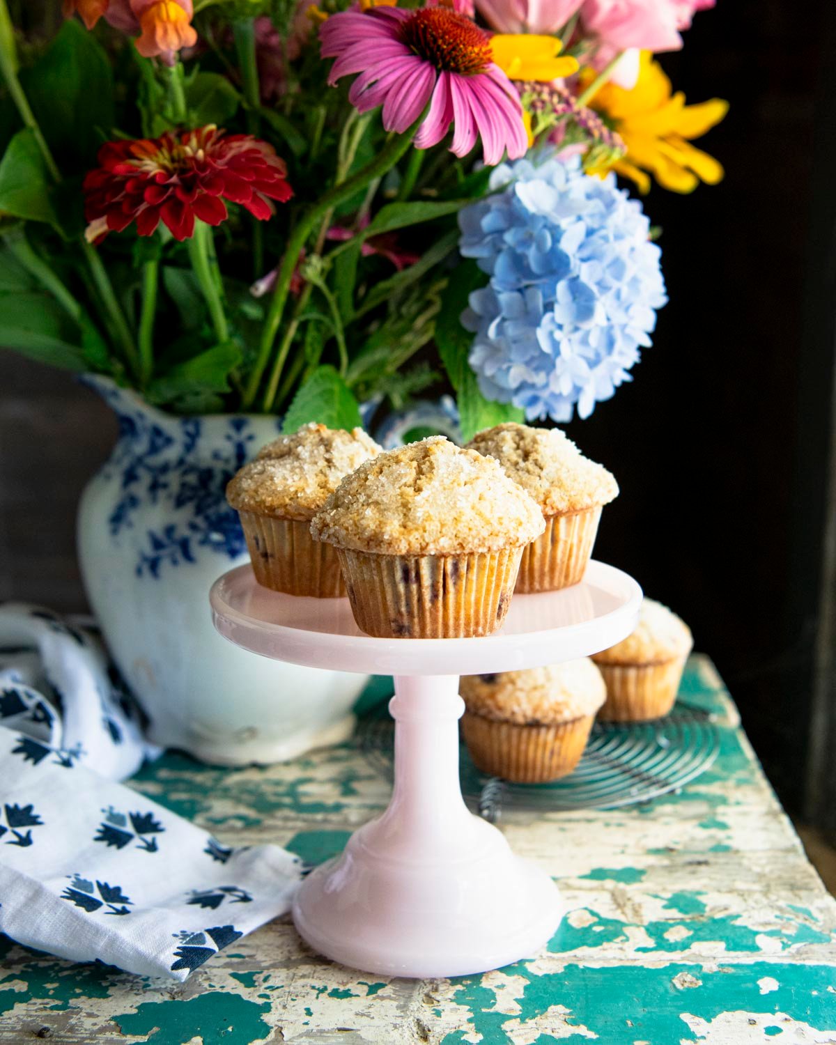 Three blackberry muffins on a small pink cake stand.