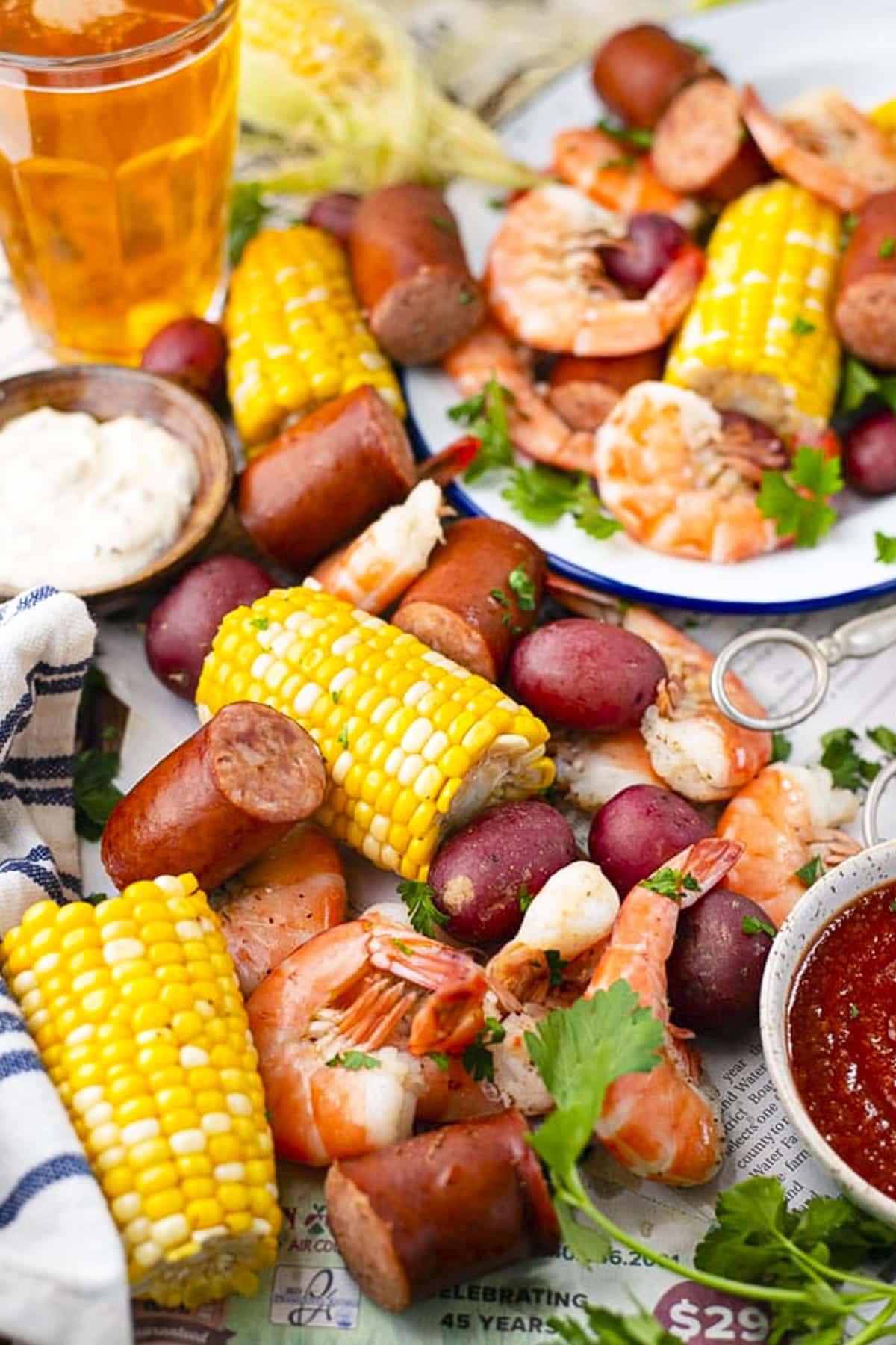 Shrimp boil recipe spread on a picnic table lined with newspapers.