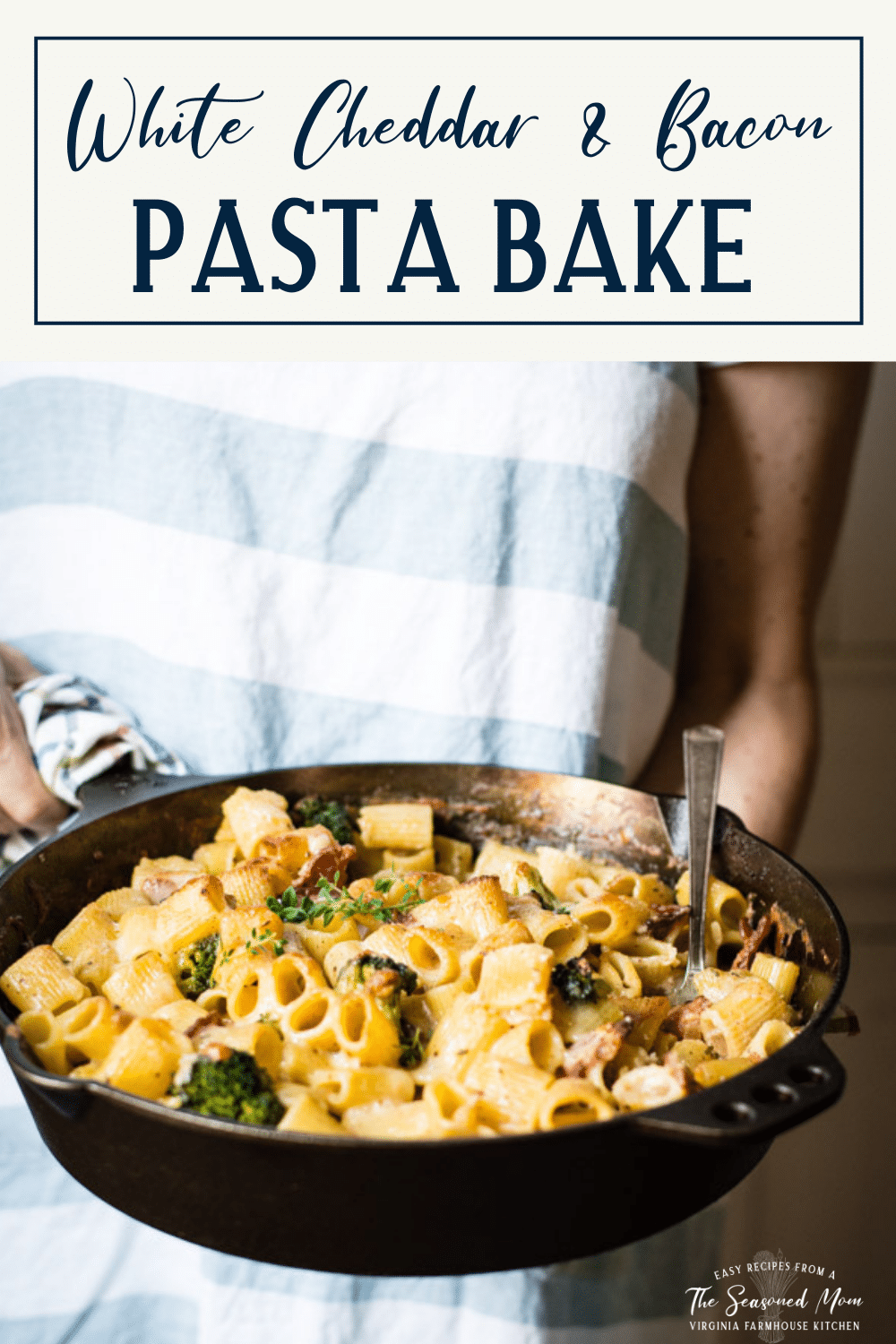 Hands holding a pan of baked pasta with cheese and a text title box at top