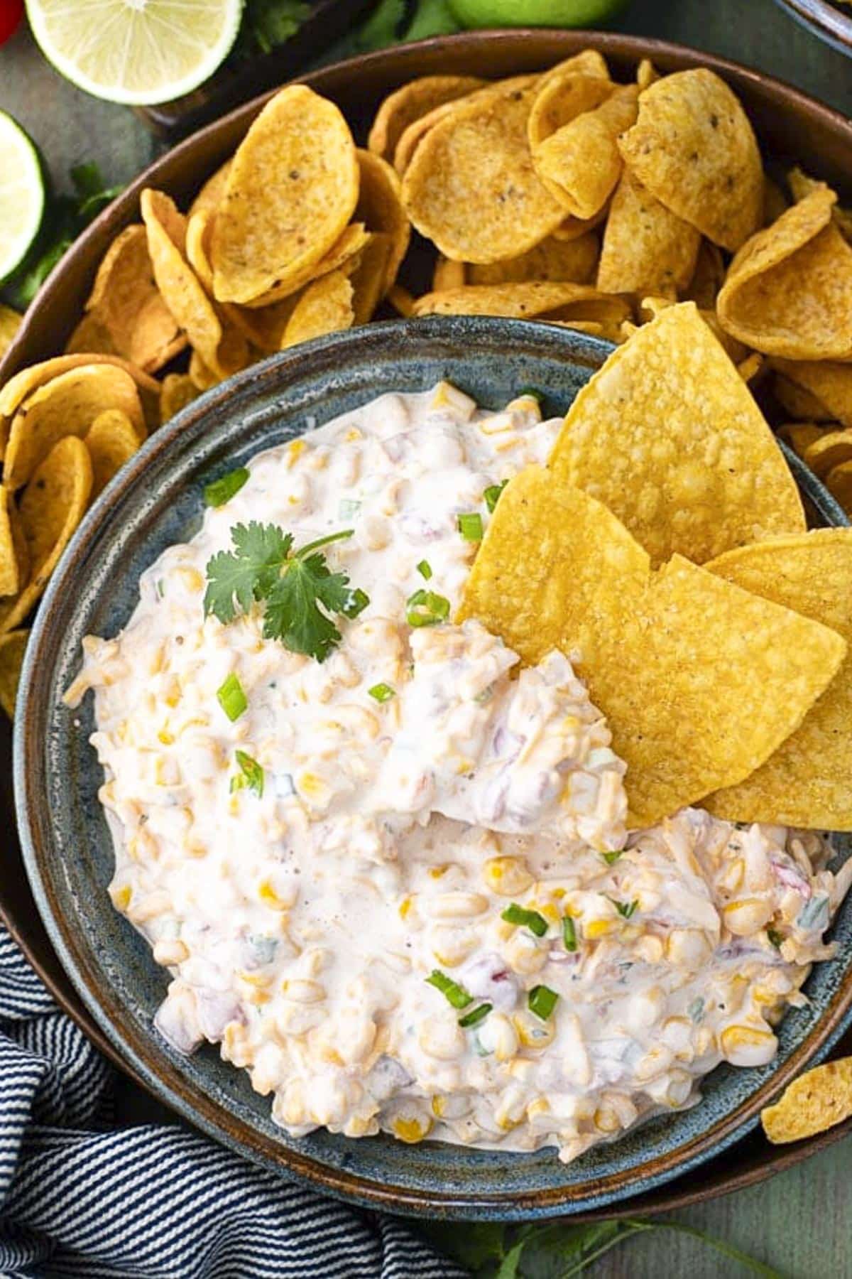 Overhead shot of an easy corn dip recipe served in a blue bowl with a side of tortilla chips.