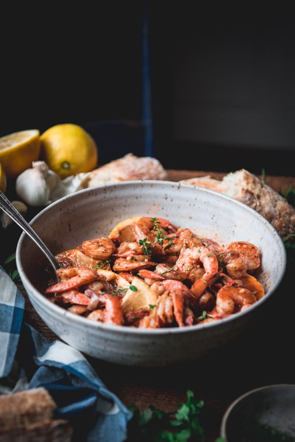 Bowl full of garlic and butter shrimp on a wooden farmhouse table.