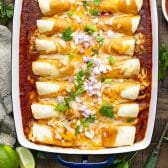 Square overhead shot of easy chicken enchiladas on a rustic wooden table.