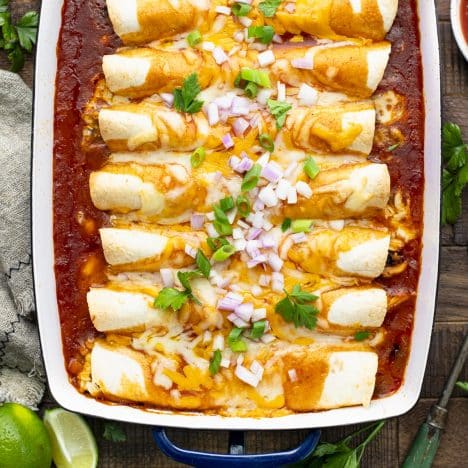 Square overhead shot of easy chicken enchiladas on a rustic wooden table.