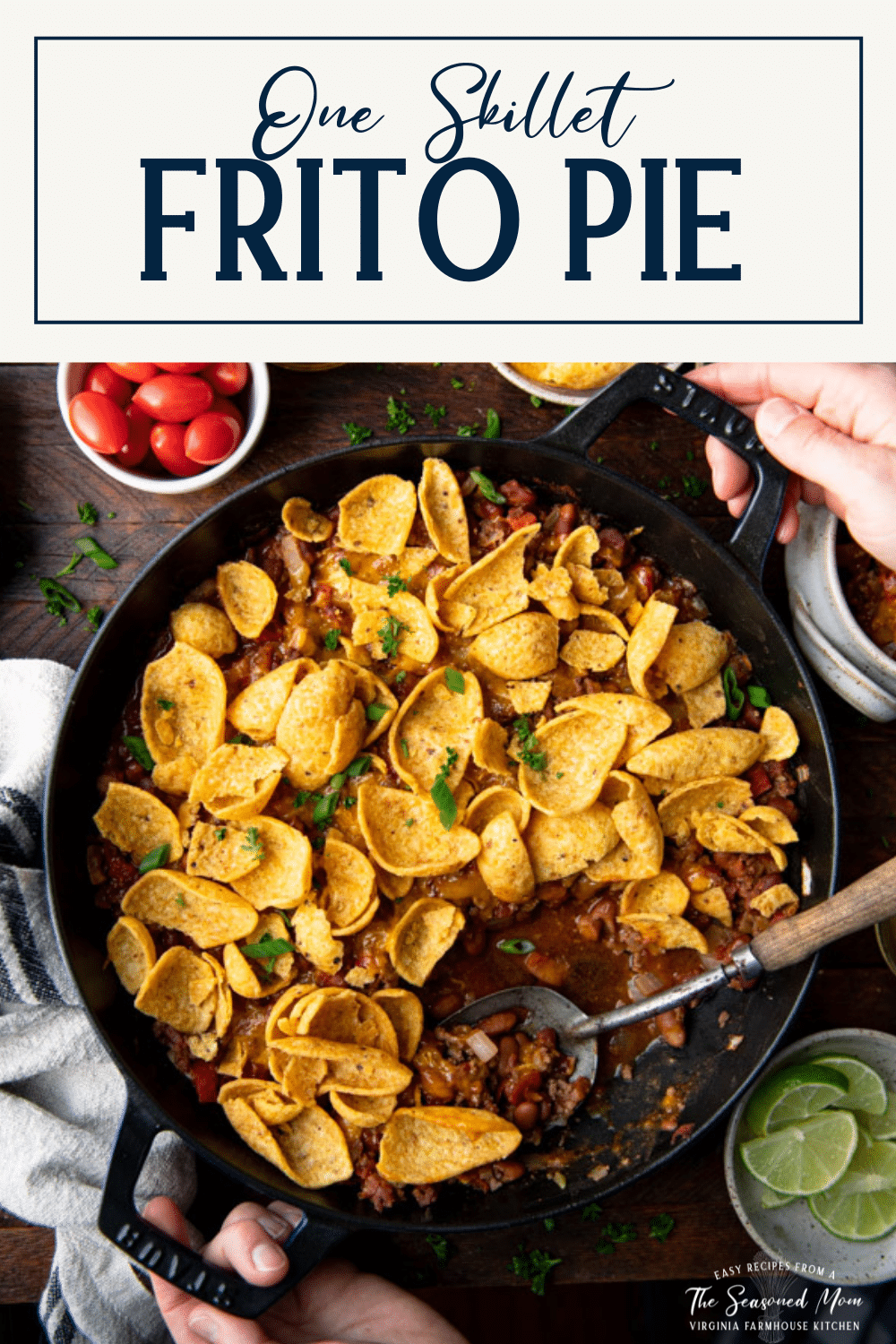 Hands holding a pan of frito pie with text title box at top.