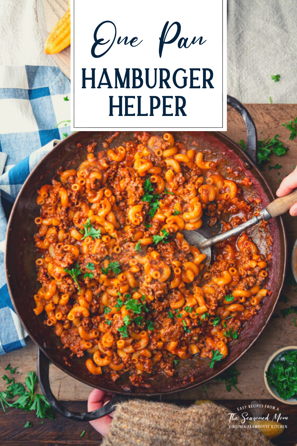 Overhead shot of hands serving homemade hamburger helper from a big skillet with text title overlay.