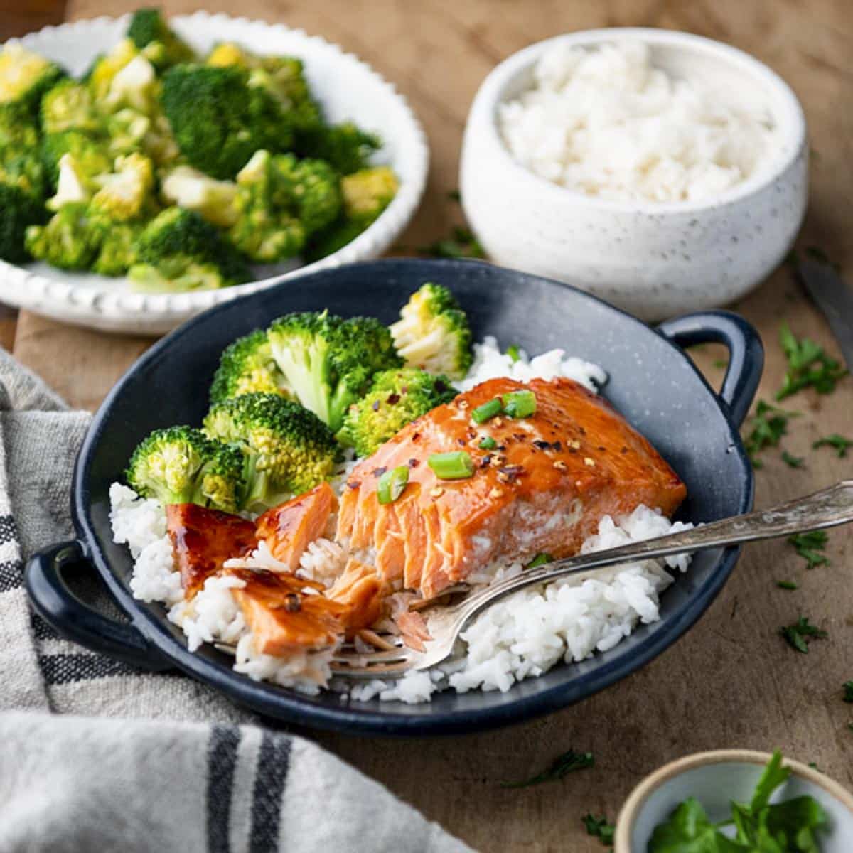 Square side shot of honey maple glazed salmon in a bowl with rice and broccoli.
