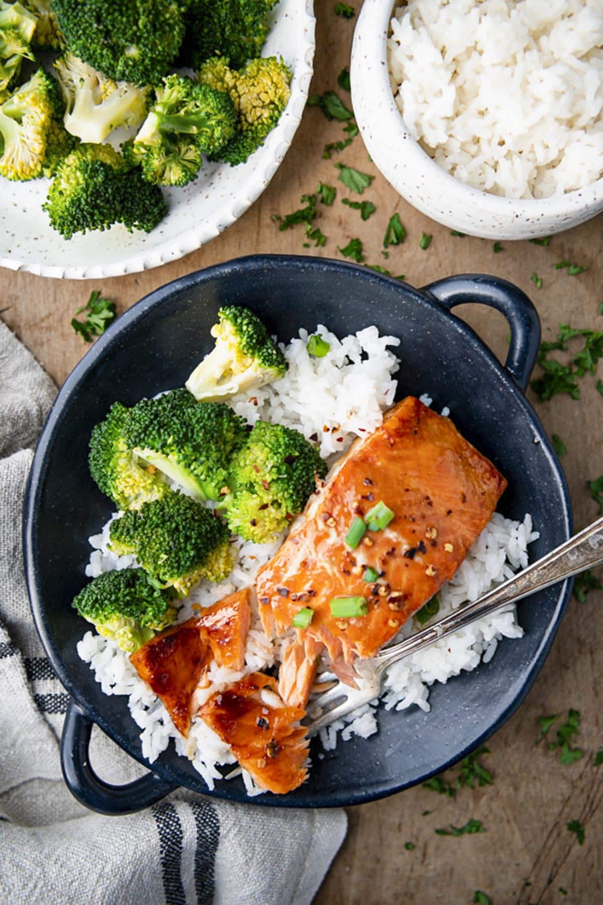 Overhead shot of honey maple glazed salmon in a black bowl with rice and broccoli.
