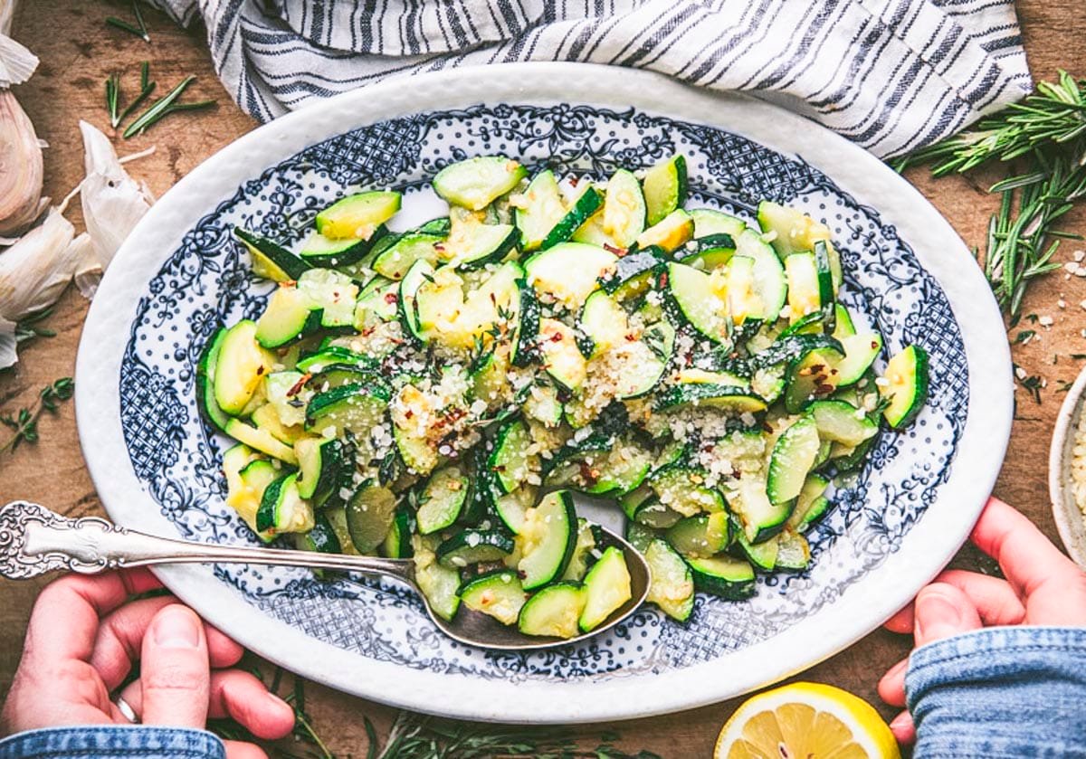 Horizontal overhead shot of sauteed zucchini on a blue and white oval plate.