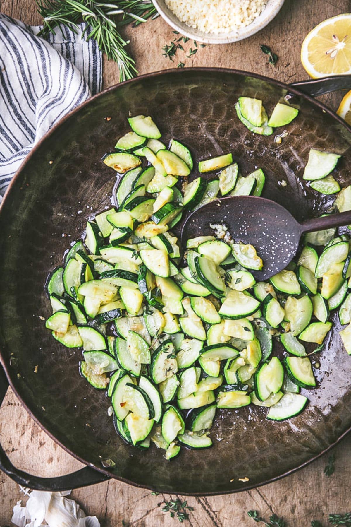 Sauteed zucchini in a cast iron skillet with a wooden spoon.