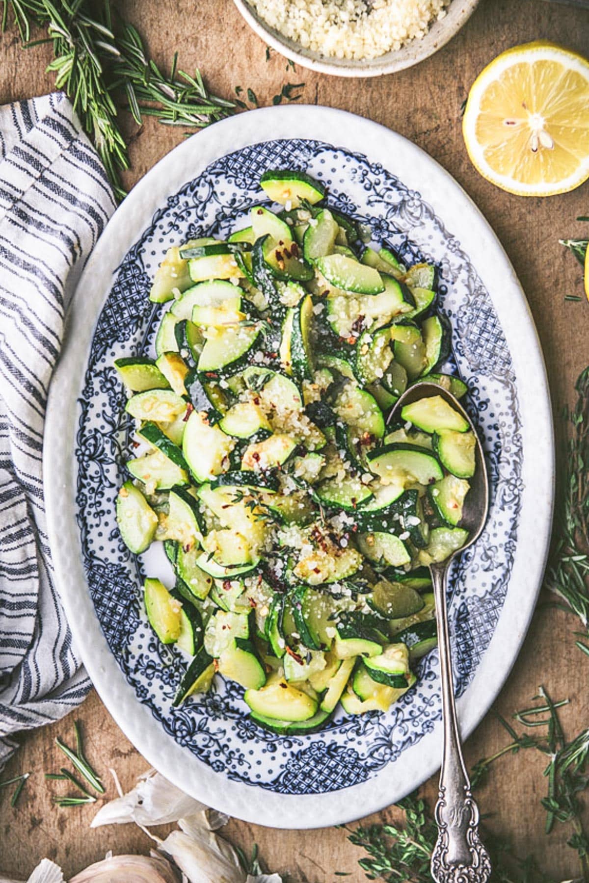 Sauteed zucchini on a blue and white plate with a serving spoon.