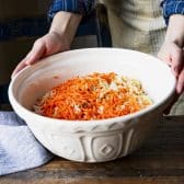 Big white bowl full of shredded cabbage and carrots.