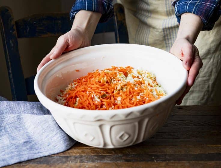 Big white bowl full of shredded cabbage and carrots.