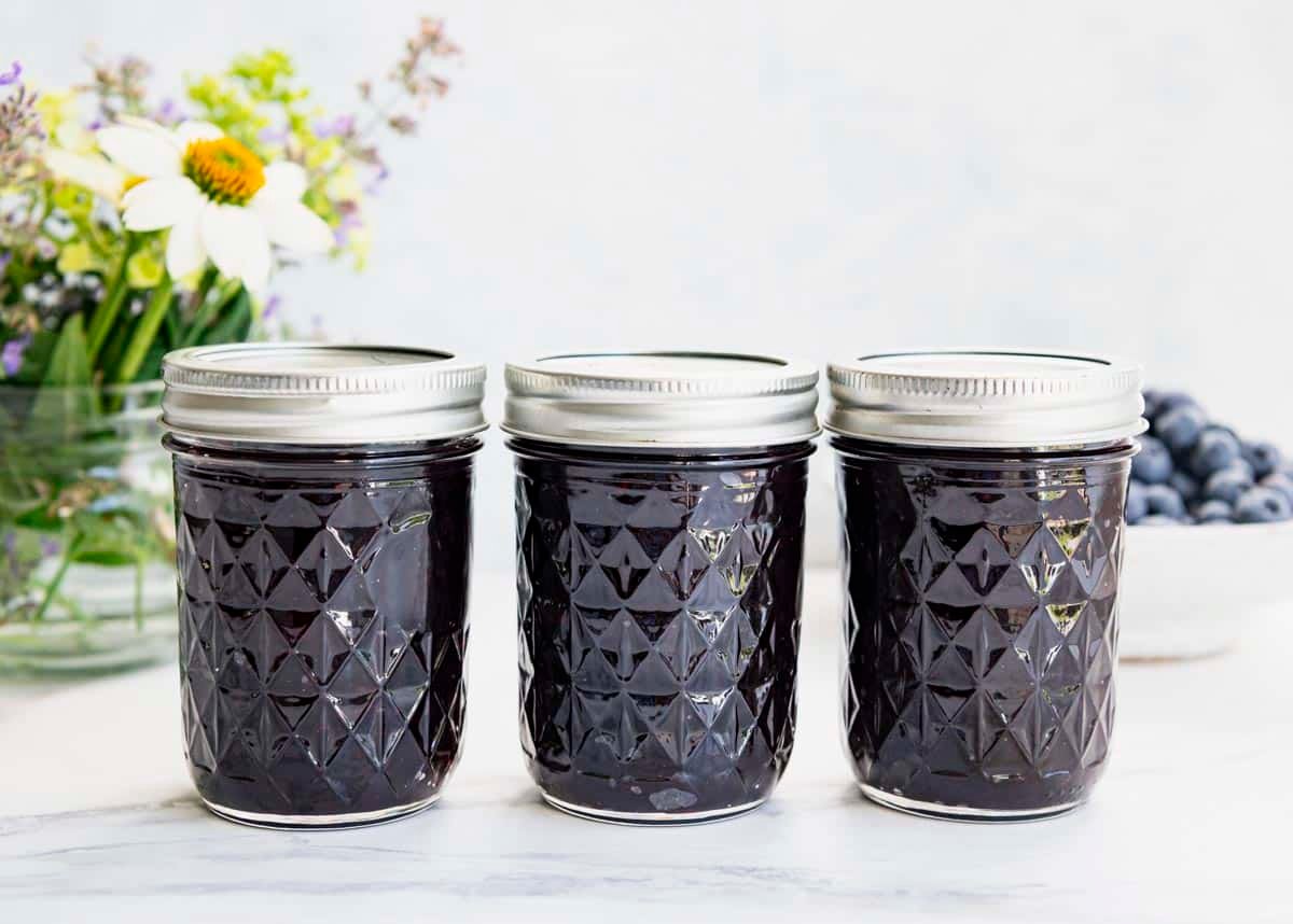 Horizontal shot of three mason jars full of the best homemade blueberry jam without pectin.