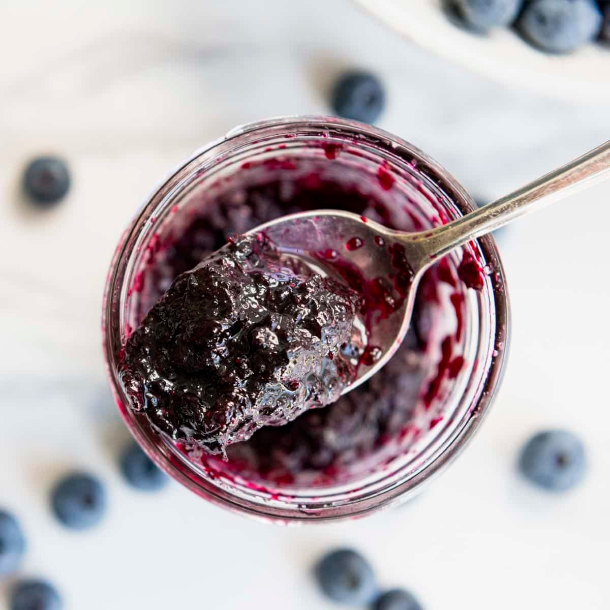 Square overhead shot of a spoonful of homemade blueberry jam.