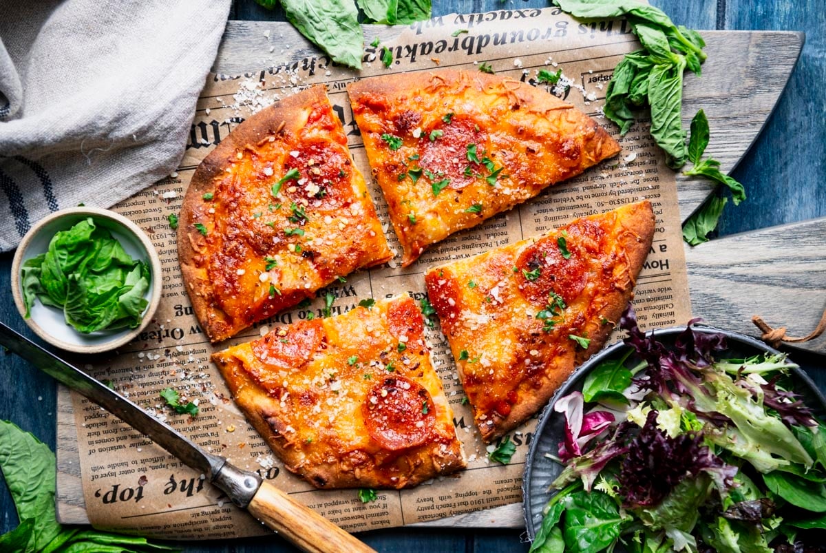 Overhead shot of flatbread pizza recipe on a table with a side salad.