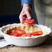 Process shot showing how to arrange tomatoes in a tomato pie.