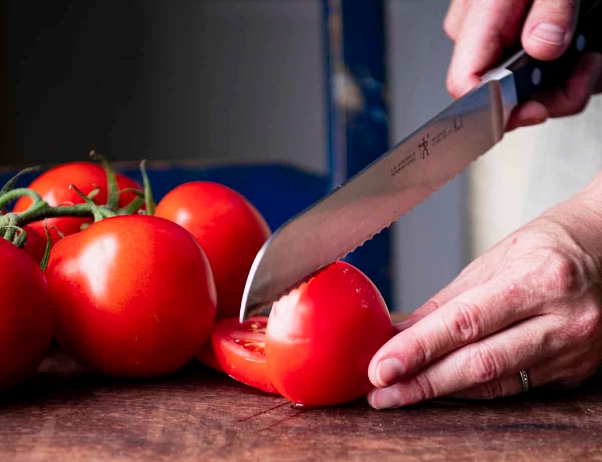 Slicing a tomato on a wooden cutting board.