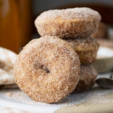 Close up square side shot of baked apple cider donuts on a platter.