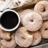 Horizontal overhead shot of a tray of baked apple cider donuts with a mug of coffee.