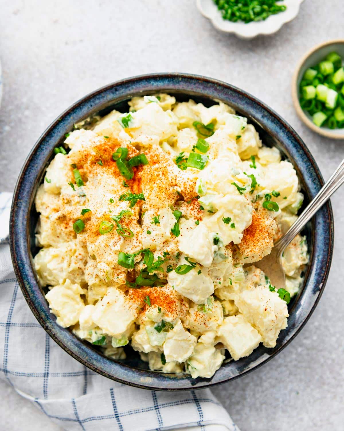Overhead image of southern potato salad recipe with sliced green onions and paprika on top.