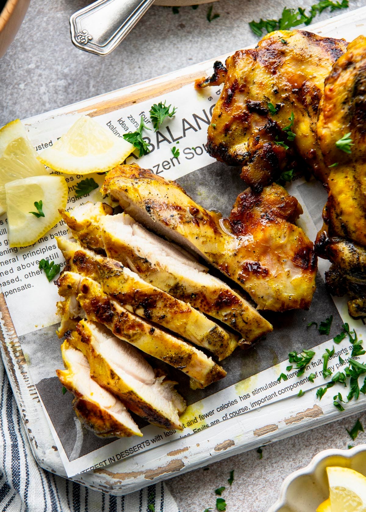 Overhead image of sliced golden chicken thigh on a white cutting board.